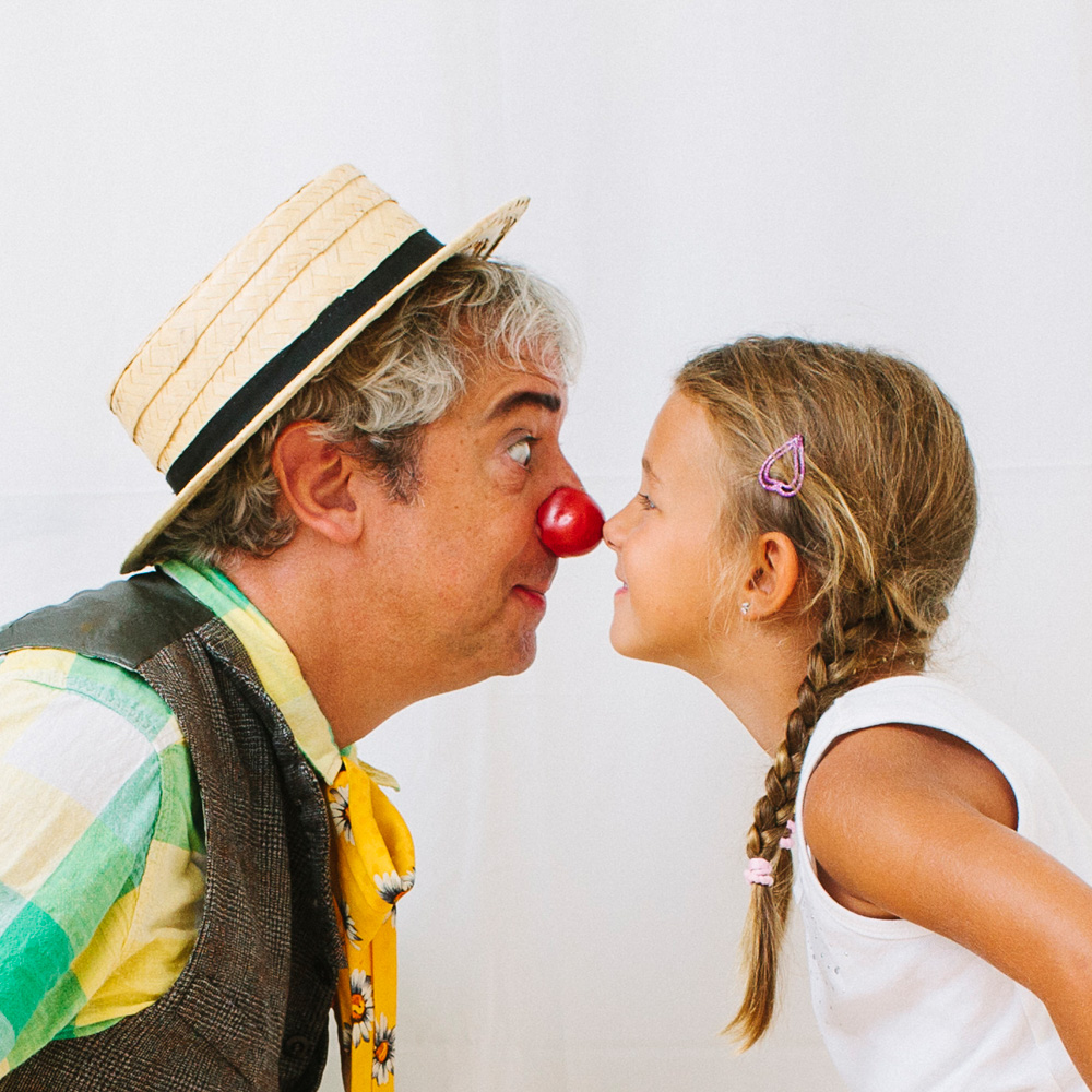 Clown mit Hut und kleines Mädchen drücken Nasen aneinander