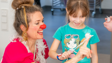 Eine Clownin der ROTE NASEN und ein Mädchen bei einer Interaktion.