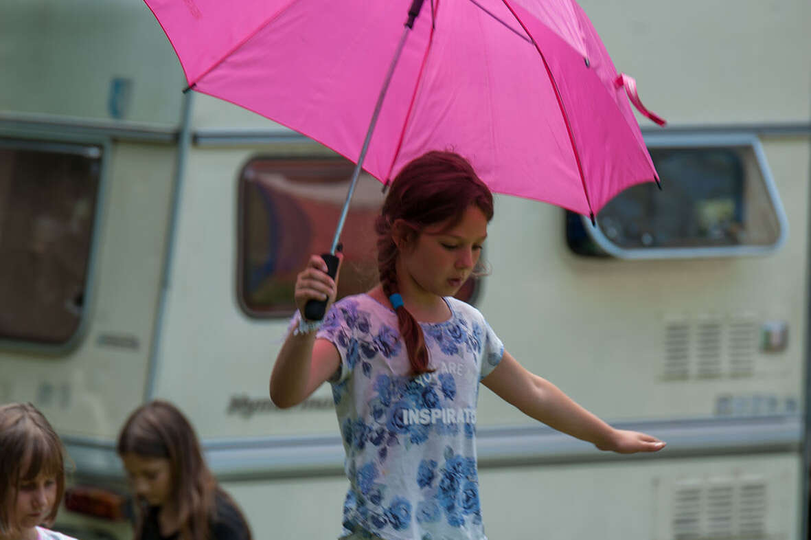 Mädchen mit pinkem Regenschirm balanciert auf einer Slackline