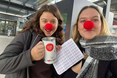 Zwei Schülerinnen mit roter Nasen und Spendendose beim Spendensammeln.