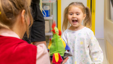 Ein kleines Mädchen, das lacht mit Clownin Lilo und ihrer Handpuppe.