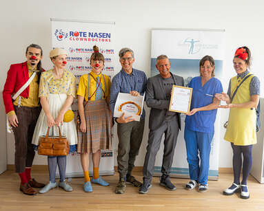 Andreas Rauter, Regionaler Programmleiter von ROTE NASEN Tirol, überreichte Harald Sinnhuber (Pflegedirektor des BKH St. Johann i.T.) und Sara Kranebitter (Pflegebereichsleitung Kinder- und Jugendheilkunde des BKH St. Johann i.T.) stellvertretend für das gesamte medizinische Personal eine Auszeichnung für die hervorragende Zusammenarbeit.