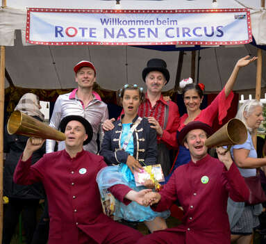 ROTE NASEN Clowns stehen vor dem Zelt des ROTE NASEN Sommercircus