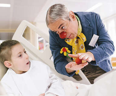 Zaubernder Clown unterhält Bub am Weg in den OP