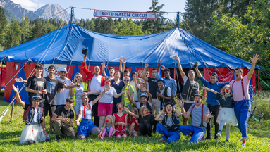Gruppenbild vor einem ROTE NASEN Circus-Zelt für Kinder und Jugendliche.