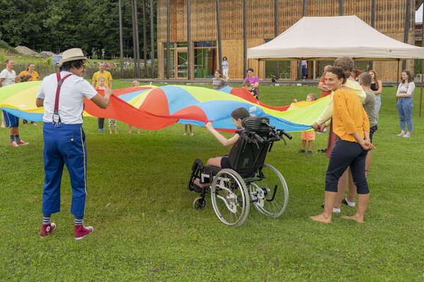 ROTE NASEN Künstler*innen mit kleinen Langzeitpatient*innen im Spiel mit einem großen Tuch.