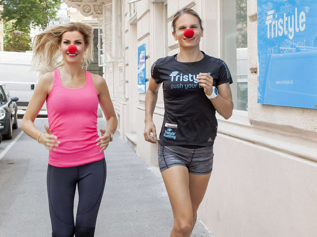 Zwei Frauen in Sportkleidung und mit roten Schaumstoffnasen laufen auf die Kamera zu
