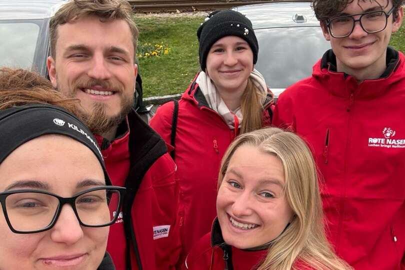 5 Werber:innen in ROTE NASEN Jacken lächeln.