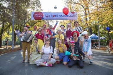 ROTE NASEN-Clown*innen posieren gemeinsam auf der Wiener Prater-Hauptallee.