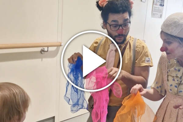 Zwei Clowns mit Tüchern im Spital bei einem kleinen Mädchen.
