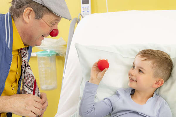 ROTE NASEN-Clown Guido und ein Junge, der eine rote Schaumstoffnase in der Hand hält.
