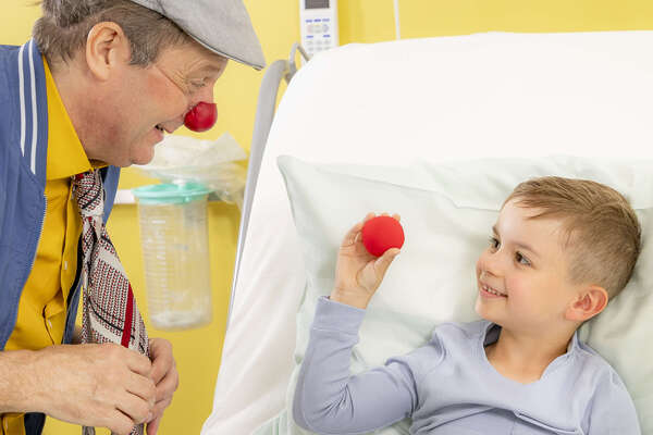 ROTE NASEN-Clown Guido und ein Junge, der eine rote Schaumstoffnase in der Hand hält.