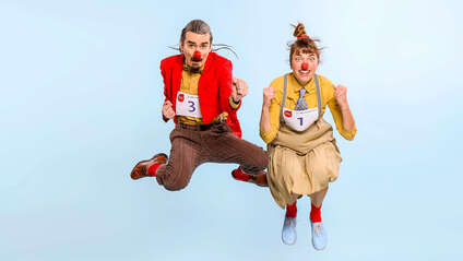 Zwei Clowns springen in die Luft.