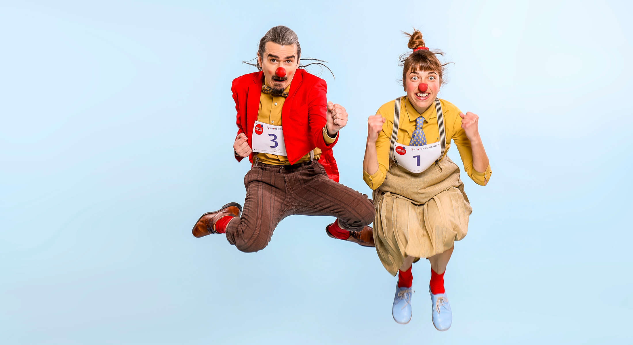 Zwei Clowns springen in die Luft.