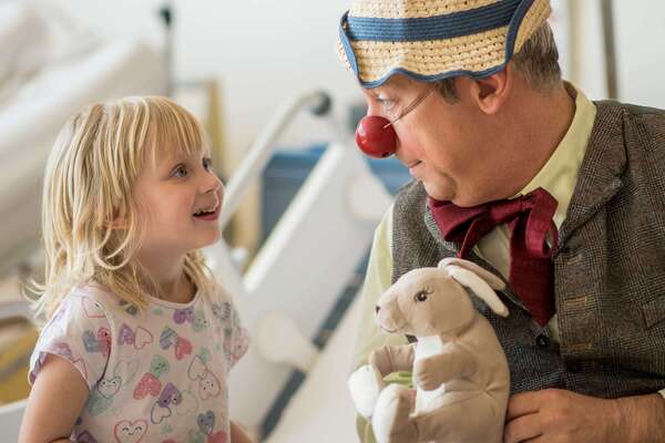 ROTE NASEN-Clown Rudi und ein kleines Mädchen in einem Krankenzimmer.