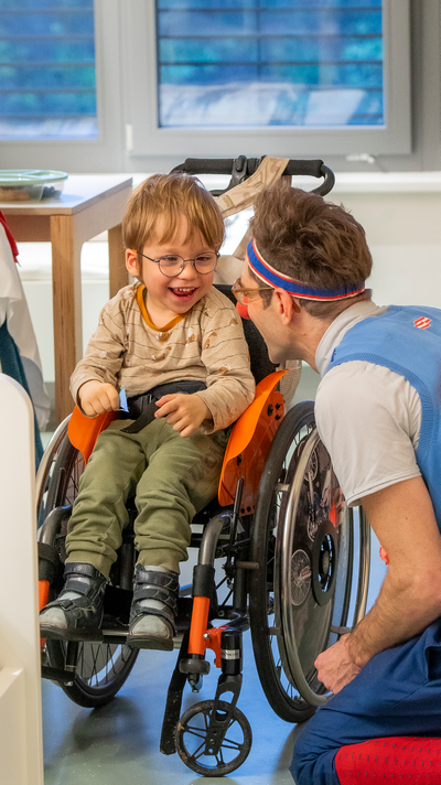 Junge in Rollstuhl lächelnd mit Clown