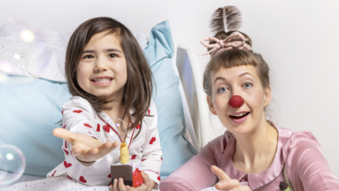 ROTE NASEN-Clownin Huberta und ein Kind, dass eine Spielzeugtorte in den Händen hält.