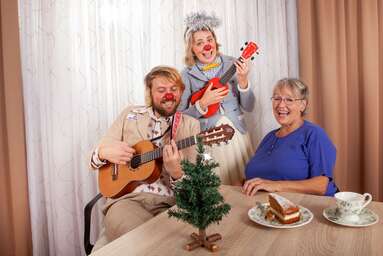 Clowns Lasse und Trixie mit Gitarre beim gemeinsamen Singen mit einer Seniorin.