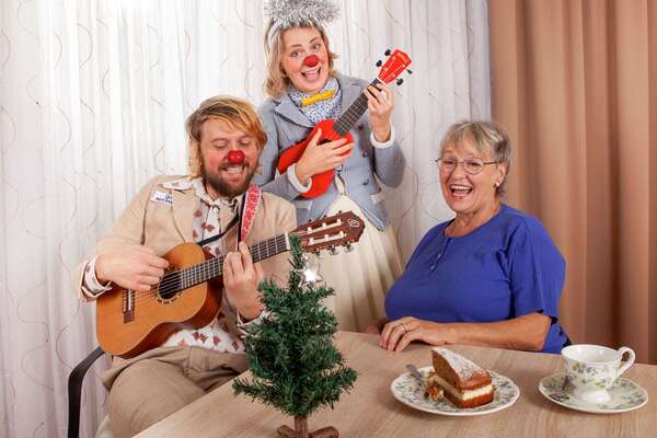 Clowns Lasse und Trixie mit Gitarre beim gemeinsamen Singen mit einer Seniorin.