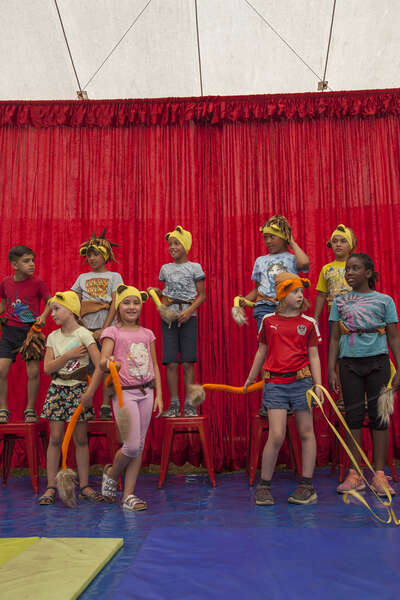 Mehrere Kinder stehen auf der Bühne im Sommerzirkus-Zelt und führen eine Show aus.
