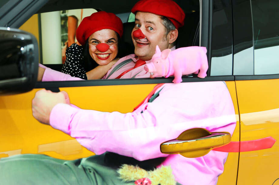 Clownin und Clown sitzen gemeinsam in einem Auto