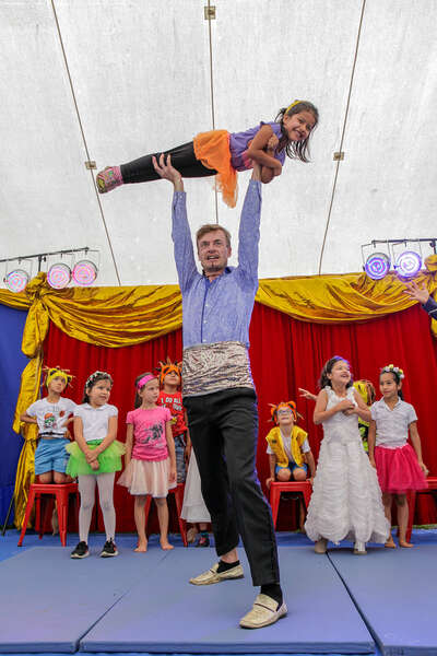 Ein Clown hebt ein kleines Mädchen hoch und hält sie über seinem Kopf in die Luft