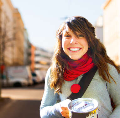 Schülerin die lächelnd auf der Straße mit einer Spendendose und roter Schaumstoffnase steht