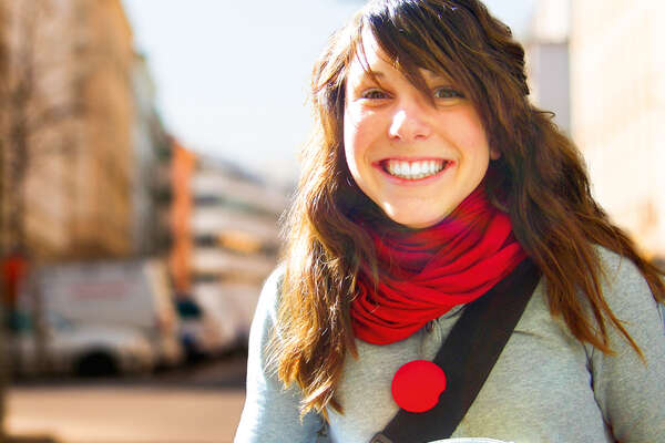 Schülerin die lächelnd auf der Straße mit einer Spendendose und roter Schaumstoffnase steht