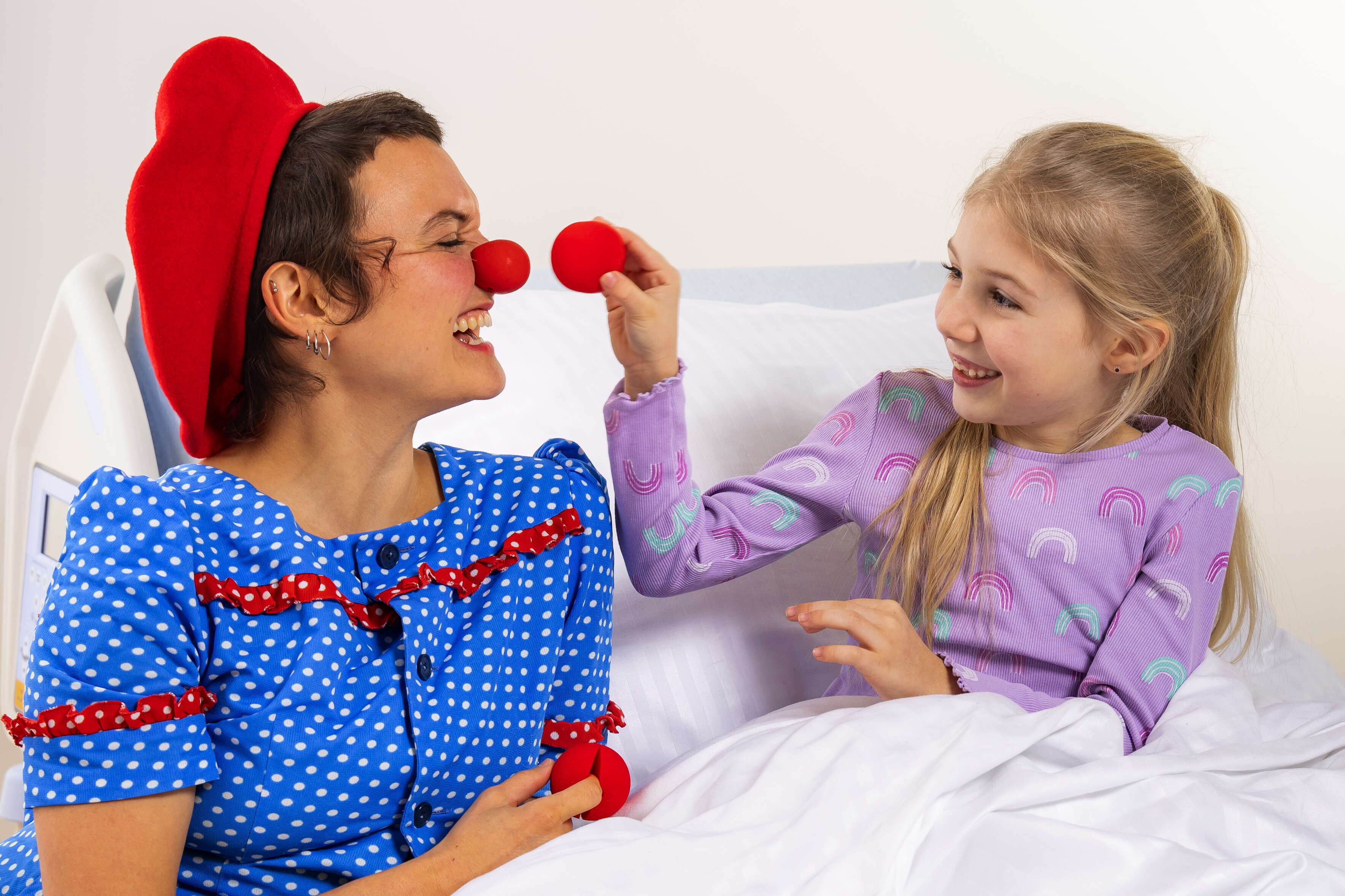 Ein Kind mit einer Clownin im Spital. Beide lachen.