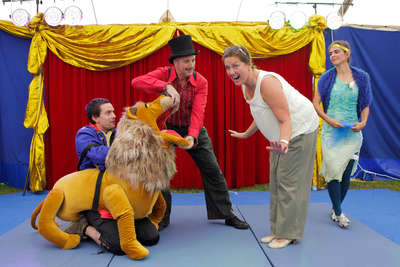 Eine Zuschauerin des Zirkus steht vor einem Clown im Plüschlöwenkostüm und macht einen ängstlich-überraschten Gesichtsausdruck