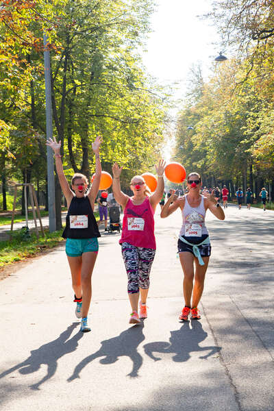 drei Läuferinnen strecken beim Laufen ihre Hände in die Höhe