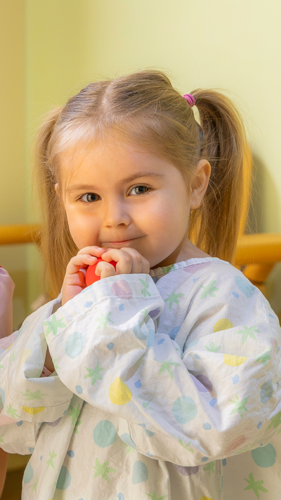 Ein kleines Mädchen mit einer roten Nase in der Hand.