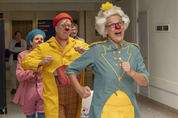 ROTE NASEN Clowns in bunten Kostümen laufen fröhlich lachend durch einen Flur.