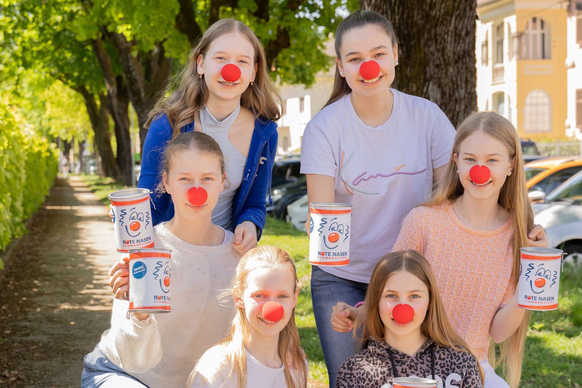 Eine Gruppe von sechs Mädchen mit Spendendosen und roter Nase.