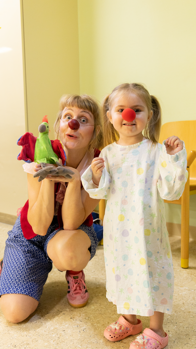 Ein kleines Mädchen mit einer roten Nase neben Clownin Lilo und ihrer Handpuppe.