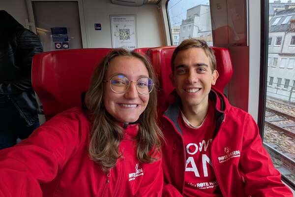 Zwei ROTE NASEN Fundraiser:innen in ROTE NASEN Jacken, die in die Kamera lächeln.