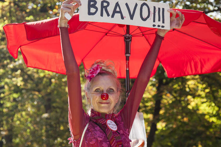 NASE AUF UND LAUF! Clownin hält ein Bild mit der Aufschrift Bravo in der Hand