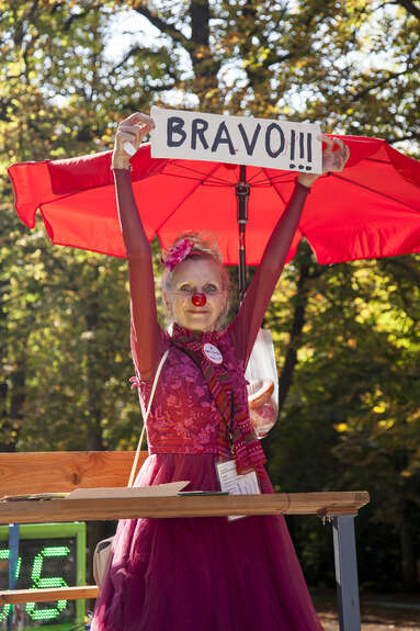 Clownin hält ein Bild mit der Aufschrift Bravo in der Hand