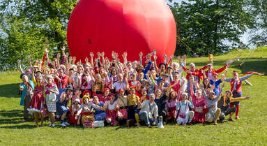 Gruppenfoto der ROTE NASEN-Clowns vor einer großen aufblasbaren roten Nase.