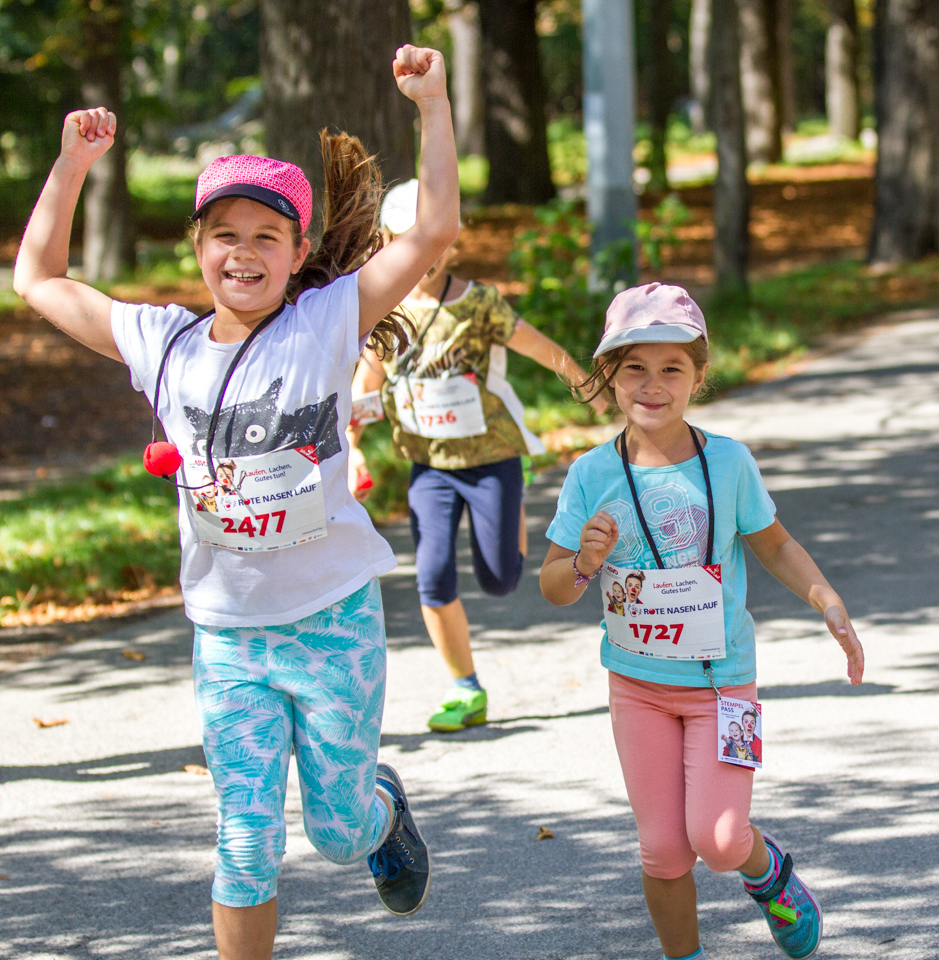 Zwei Kinder sind lachend auf der Laufstrecke unterwegs