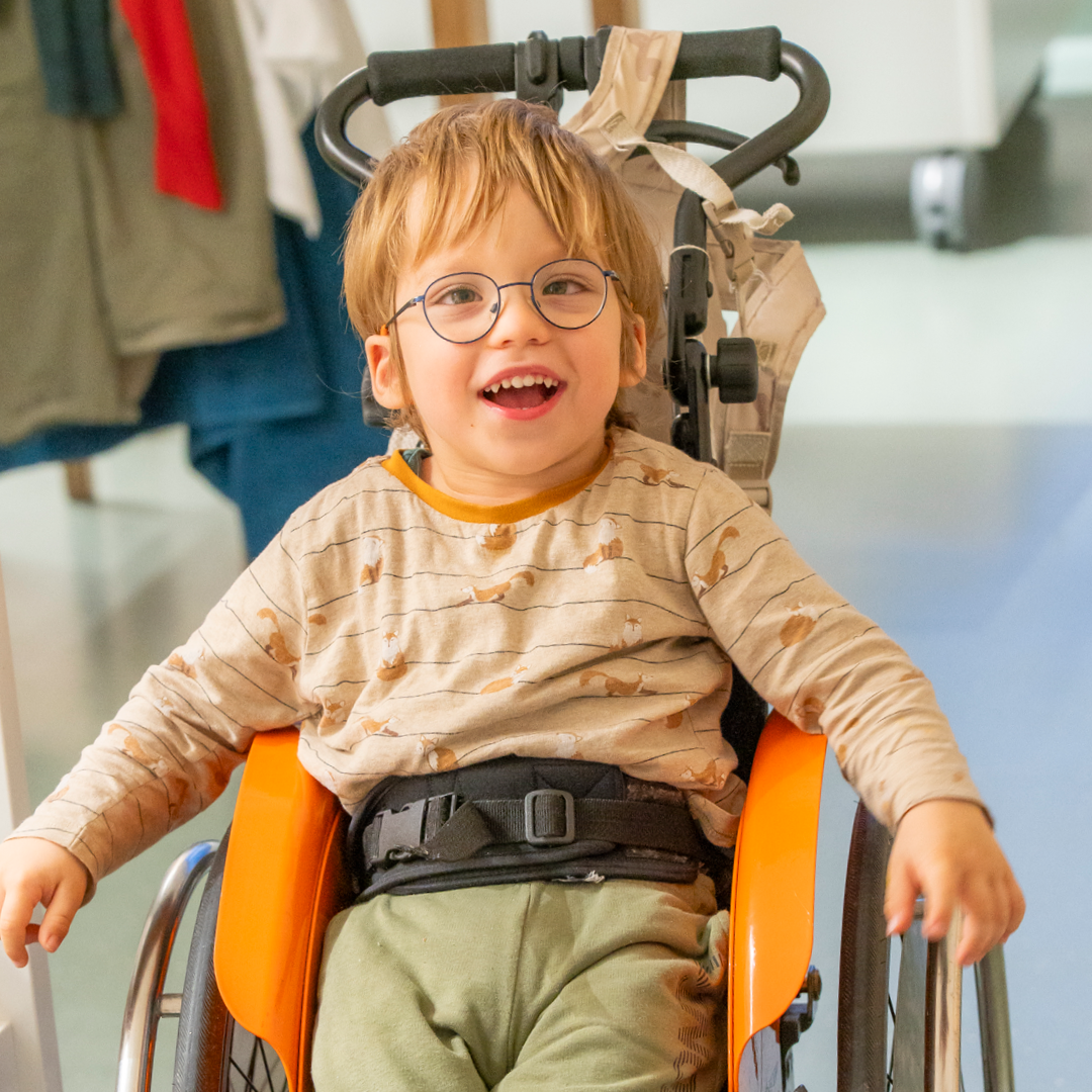 Junge in Rollstuhl lächelt in die Kamera.