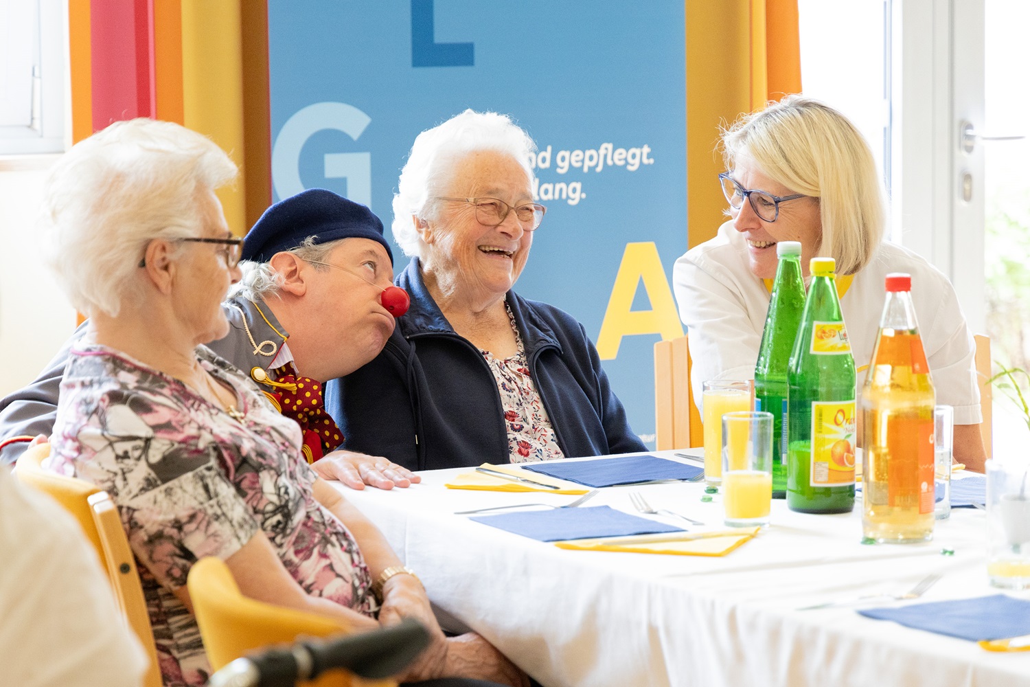ROTE NASEN-Clown Rudi zu Besuch in einem Pflegeheim mit zwei älteren Damen und einer Angestellten.