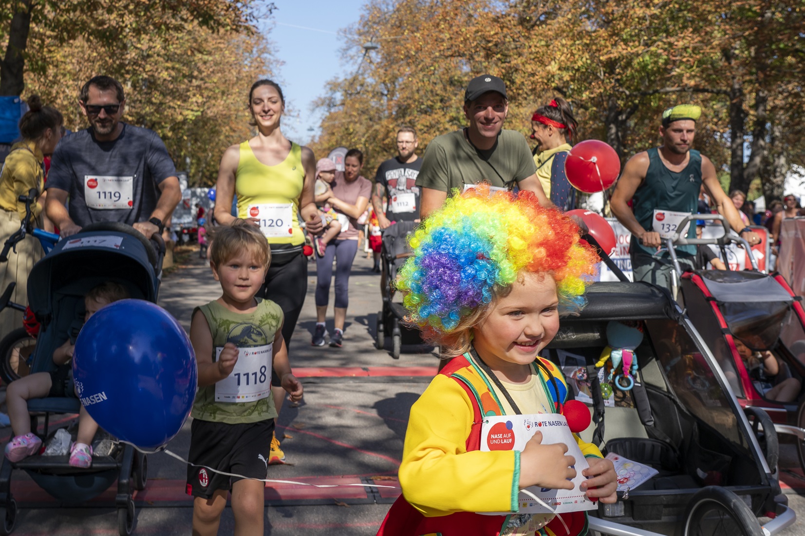 Teilnehmende am Wiener ROTE NASEN-Lauf 2025, darunter ein Kind mit einer bunten Perücke.