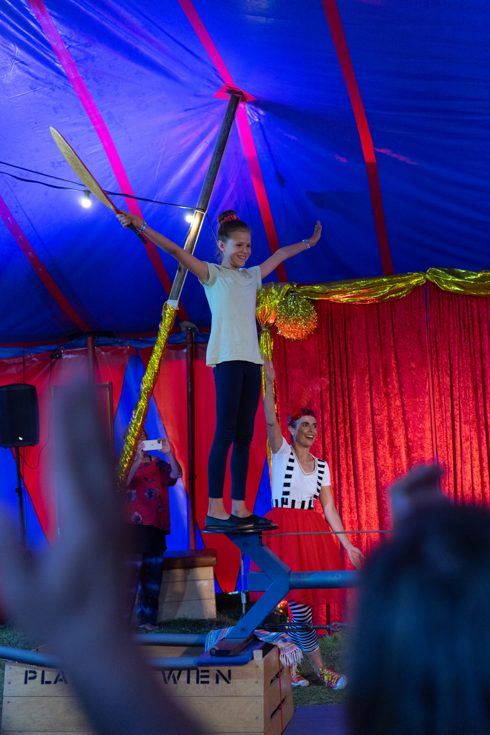 Ein Mädchen balanciert auf einem Seil, neben ihr befindet sich die ROTE NASEN-Clownin Rita.