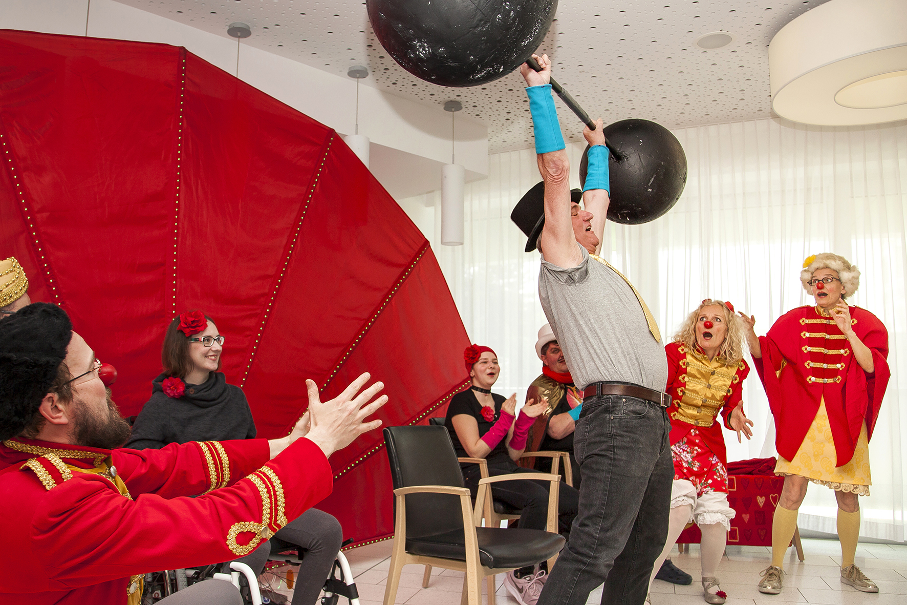Patient hebt Gewicht, Clowns und Zuschauer jubeln