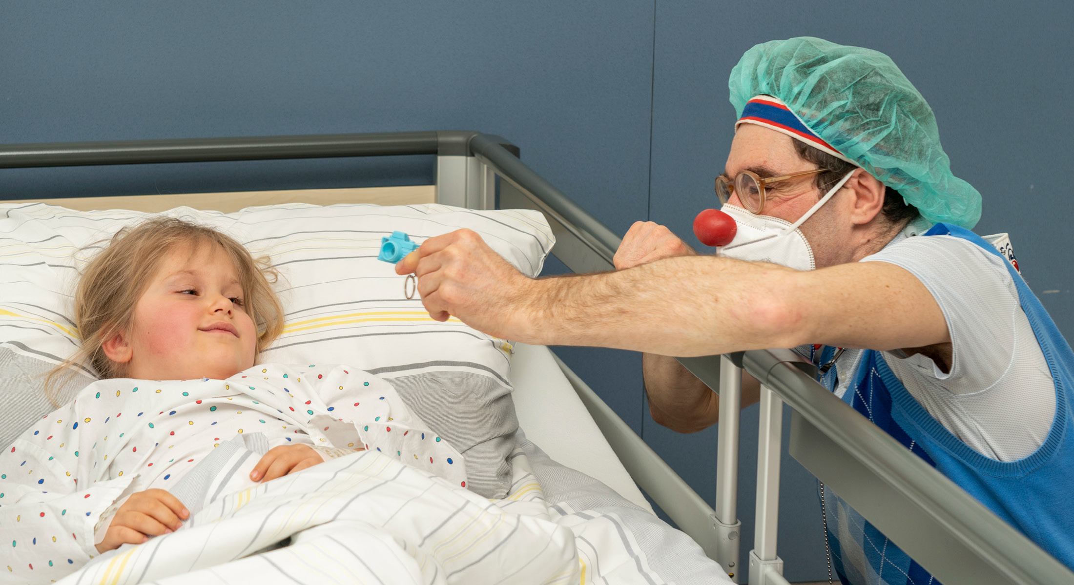 Ein Mädchen im Krankenbett wird von Clown Bernhart besucht.