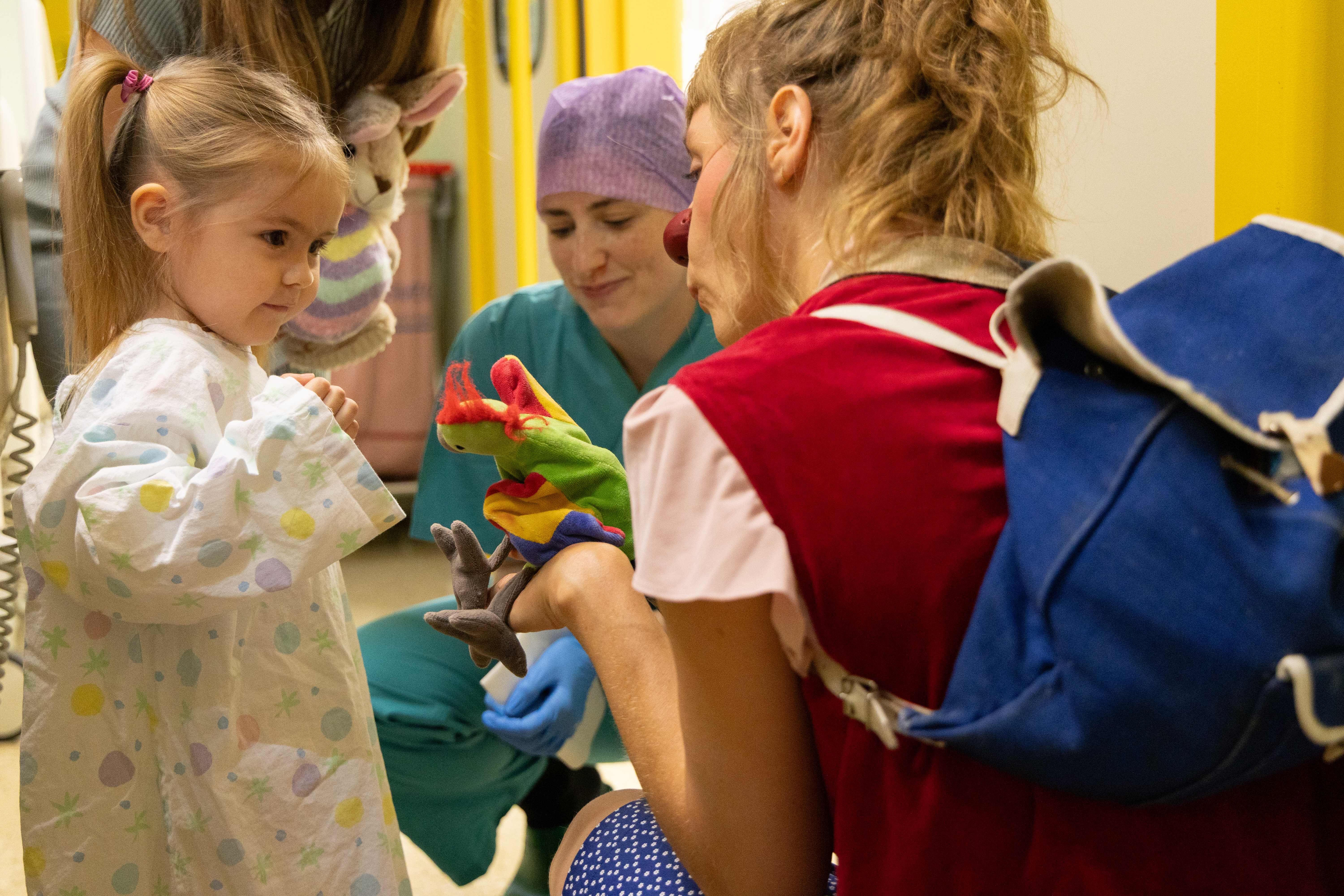 Clownin lenkt mit ihrer Handpuppe ein Kind im Spital ab.